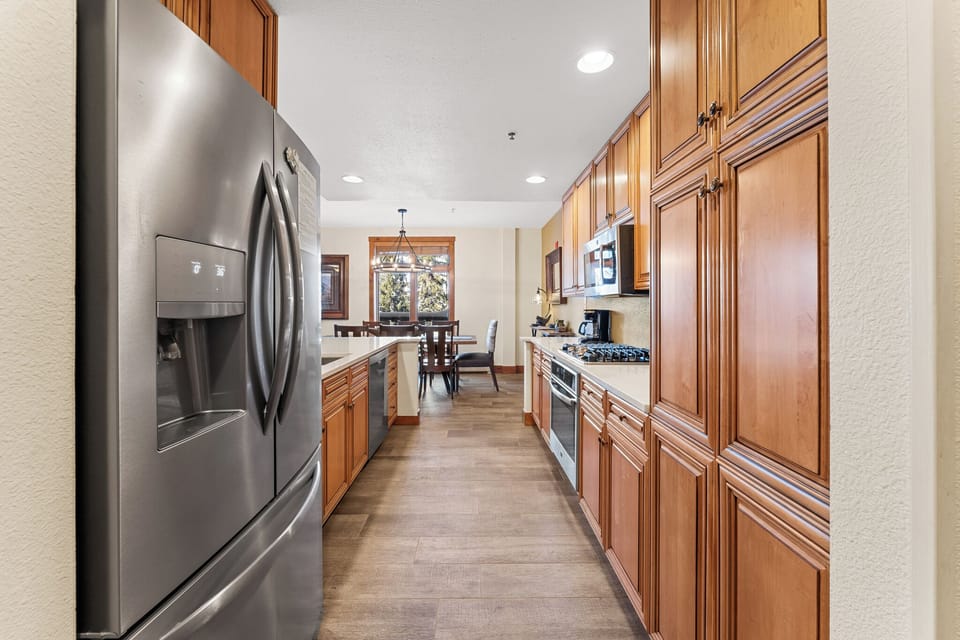 Your gourmet galley kitchen features rich wood cabinetry and stainless steel appliances, creating the perfect space for preparing memorable meals during your stay.