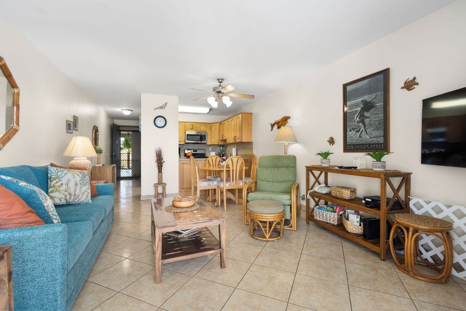 Unwind in your open-concept living space with coastal charm, where a cozy teal sofa invites relaxation and a fully equipped kitchen awaits your culinary adventures.