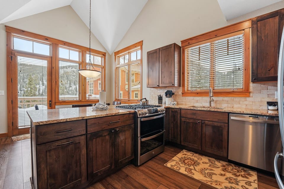 Cook gourmet meals in your fully equipped mountain kitchen with granite counters, stainless appliances, and stunning natural light streaming through wood-framed windows.
