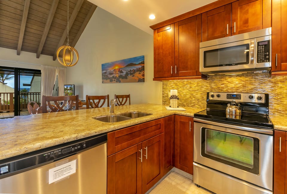 Your fully equipped kitchen awaits with granite countertops, stainless appliances, and warm wood cabinetry—perfect for preparing meals while taking in those stunning island views through the open living space.