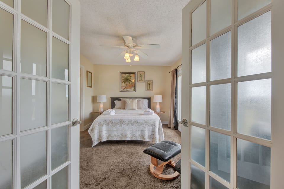 Step into your serene master bedroom where elegant French doors welcome you to peaceful nights on plush carpeting beneath a gentle ceiling fan.