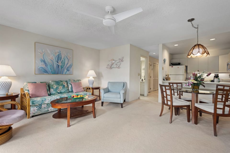 Relax in your spacious living area featuring coastal decor, comfortable seating, and a fully equipped kitchen perfect for preparing meals together during your tropical getaway.