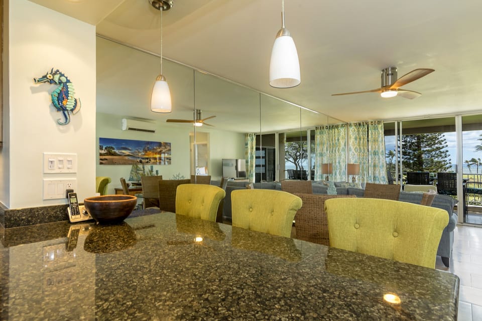 Gather around your spacious granite countertop, perfect for quick breakfasts or evening cocktails, as ocean breezes drift in from the lanai and coastal light fills your open living space.