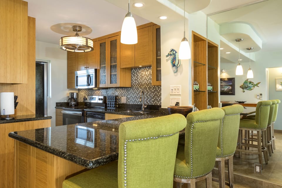 You'll love gathering around this spacious kitchen island with its gleaming granite countertops, modern appliances, and cheerful green bar seating—perfect for meals, conversation, and making memories together.