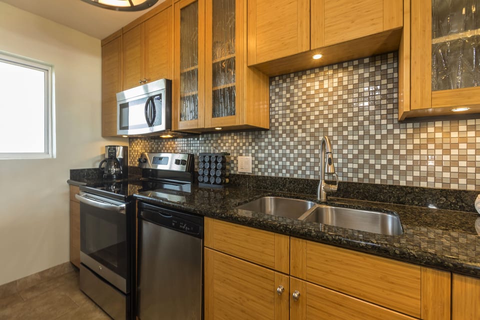 Your fully equipped kitchen features gleaming granite countertops, stainless steel appliances, and stylish mosaic tile backsplash—everything you need to whip up delicious meals during your stay.