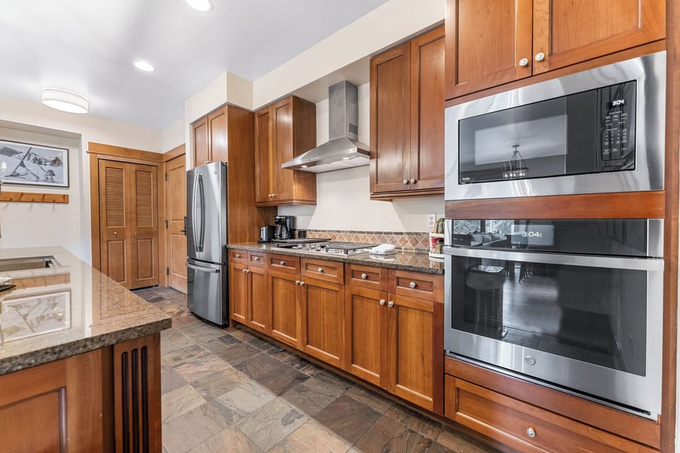 Your gourmet kitchen awaits with warm wood cabinetry, granite counters, and stainless appliances—perfect for preparing memorable meals together.