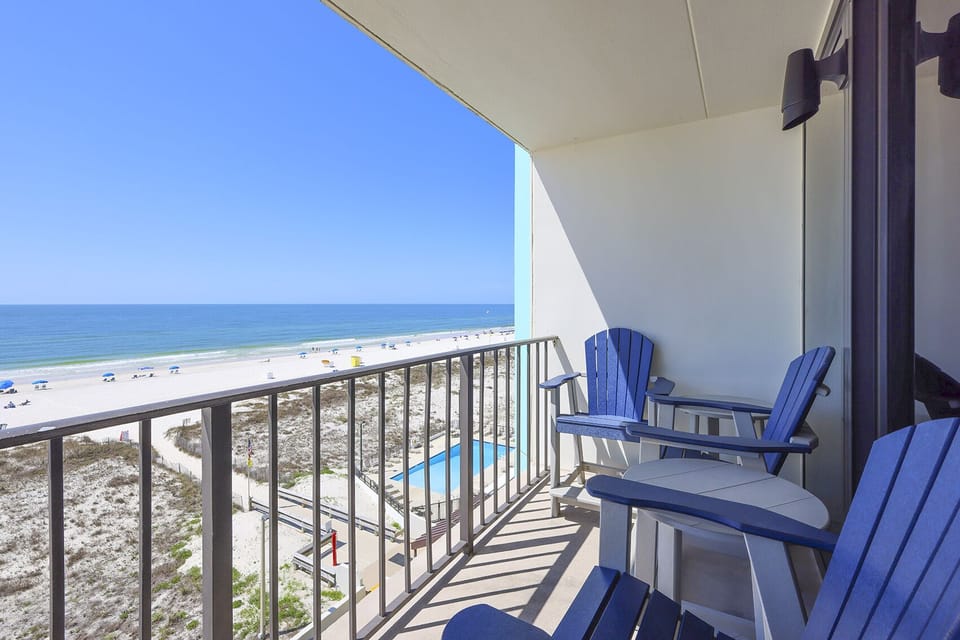 Enjoy stunning beachfront views from this balcony featuring comfortable seating, perfect for relaxation and unwinding