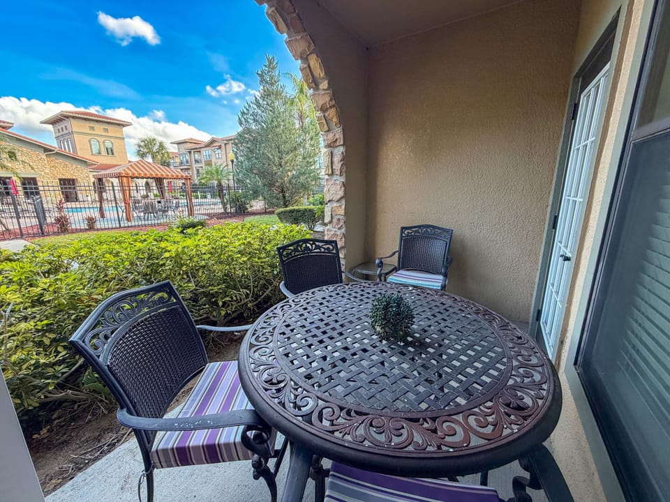 Private patio with outdoor dining table and seating overlooking resort pool area at a central Florida vacation rental near Disney.
