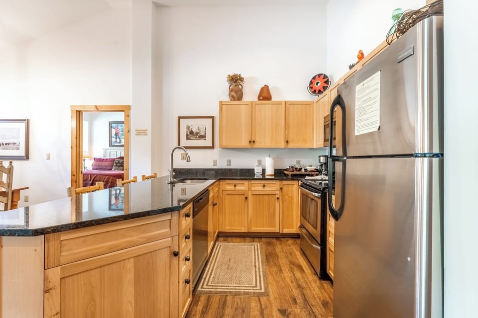Your fully equipped kitchen awaits with warm wood cabinets, granite counters, and stainless appliances—perfect for preparing memorable meals during your stay.