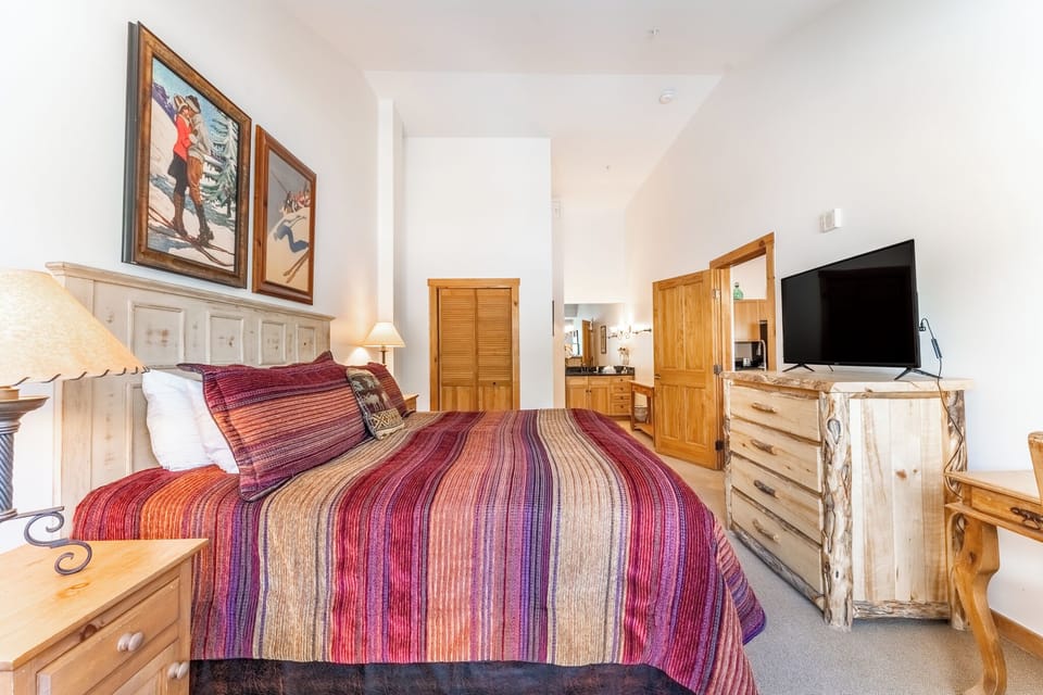 Drift into mountain dreams wrapped in colorful quilts, with ski art adorning your walls and rustic wood furniture creating that perfect alpine retreat ambiance.