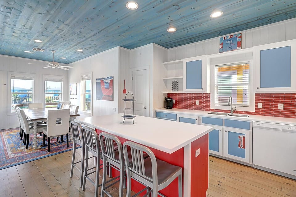 Your spacious kitchen features vibrant red accents and coastal blue ceiling where you'll love preparing meals together.