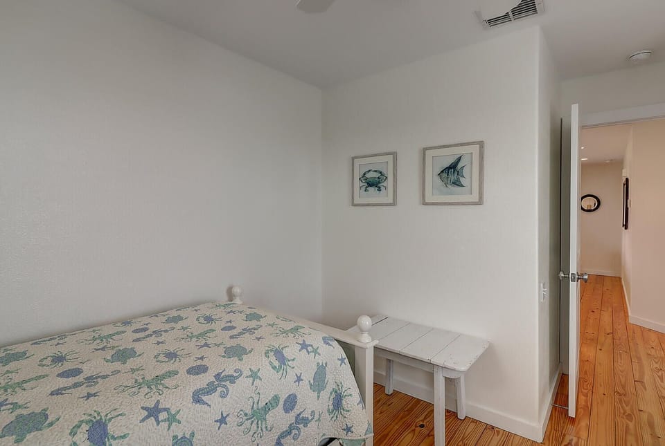 Your coastal-themed bedroom features ocean artwork and warm wood floors, creating a peaceful seaside retreat for restful nights.