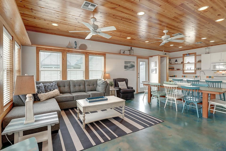 Relax in your spacious living area with coastal charm, featuring comfortable seating and an open layout that flows into the kitchen.