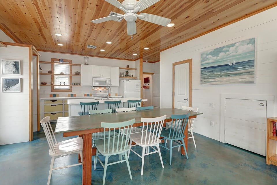 Gather around your charming dining table under vaulted wood ceilings, where coastal vibes and modern comfort create the perfect space for memorable meals.