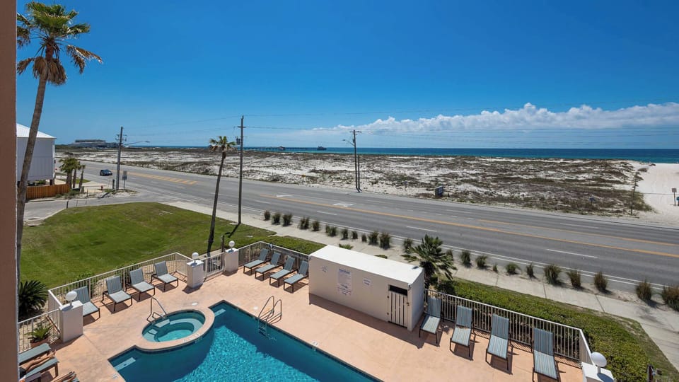 Enjoy a refreshing view of the pool and beach from this inviting balcony, perfect for relaxation and outdoor enjoyment