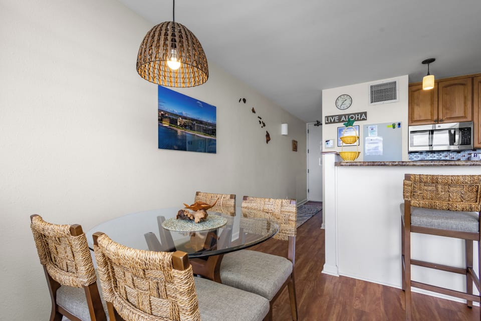 Your island-inspired dining nook features a woven pendant light, comfy wicker-backed chairs, and a kitchenette, perfect for sharing meals with ocean views nearby.