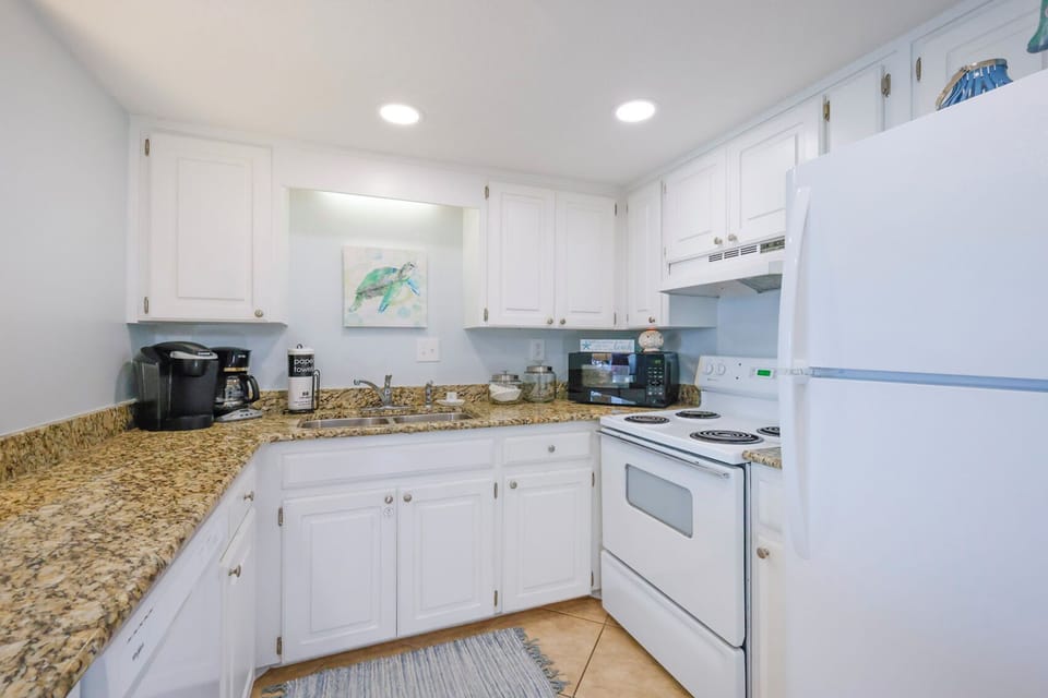The kitchen features white cabinets, granite countertops, and modern appliances, perfect for preparing meals during your stay