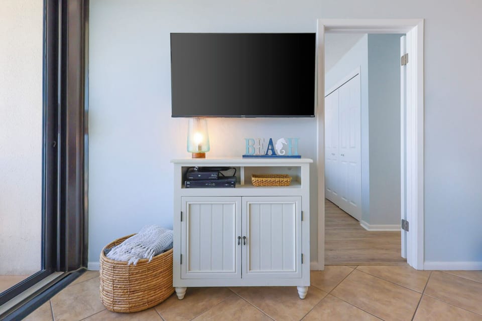 This living area features a stylish TV stand with a beach-themed decor, inviting relaxation and entertainment