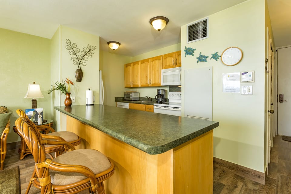 Gather around your fully-equipped kitchen featuring an open breakfast bar—perfect for morning coffee or preparing island-inspired meals in your coastal retreat.