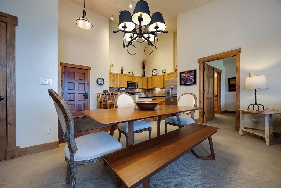 Gather around this handsome dining table with seating for everyone, bathed in warm light from a striking chandelier. The open layout flows seamlessly into your fully-equipped kitchen, perfect for memorable meals together.