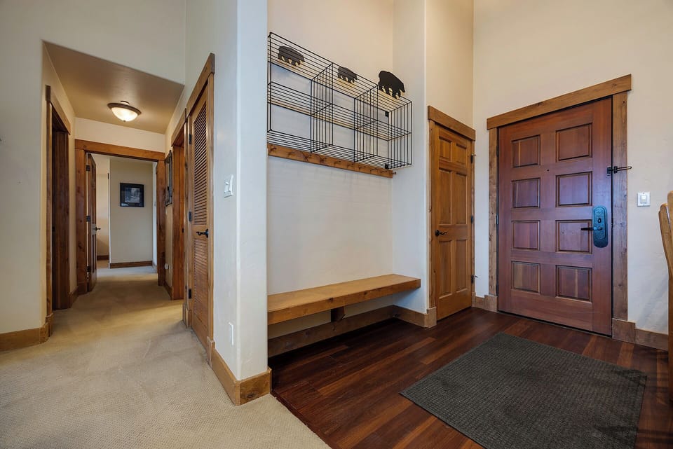 Step into your warm mountain retreat through the welcoming entryway, featuring rich hardwood floors, a convenient built-in bench, and stylish coat storage to help you settle in with ease.