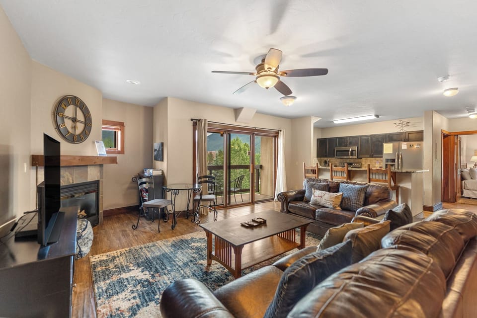 Unwind in your spacious living room with plush leather seating, a cozy fireplace, and mountain views through sliding doors.