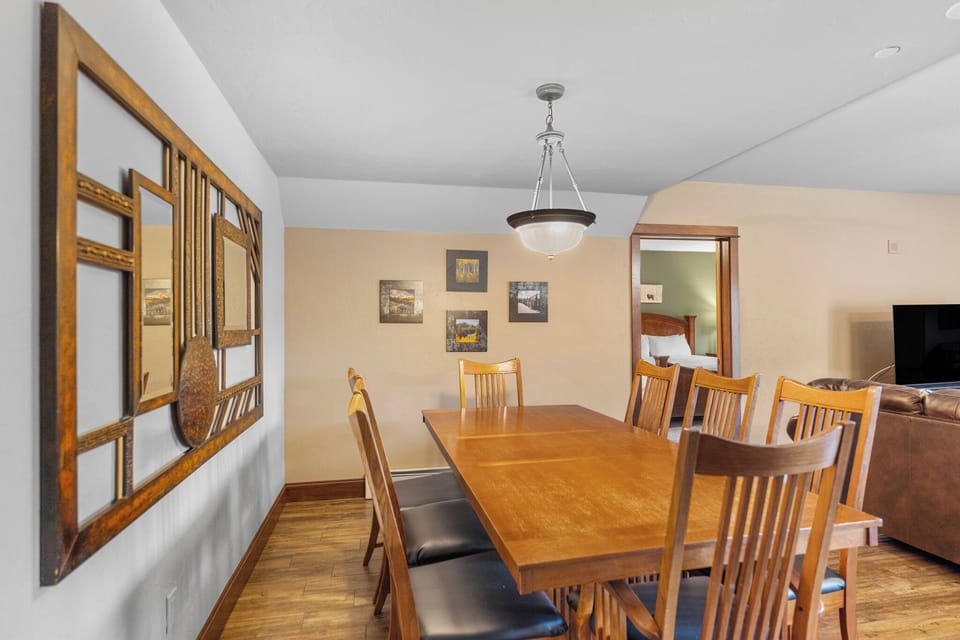 Gather around your spacious dining table for memorable meals together, with warm wood tones and artwork creating the perfect atmosphere for your stay.