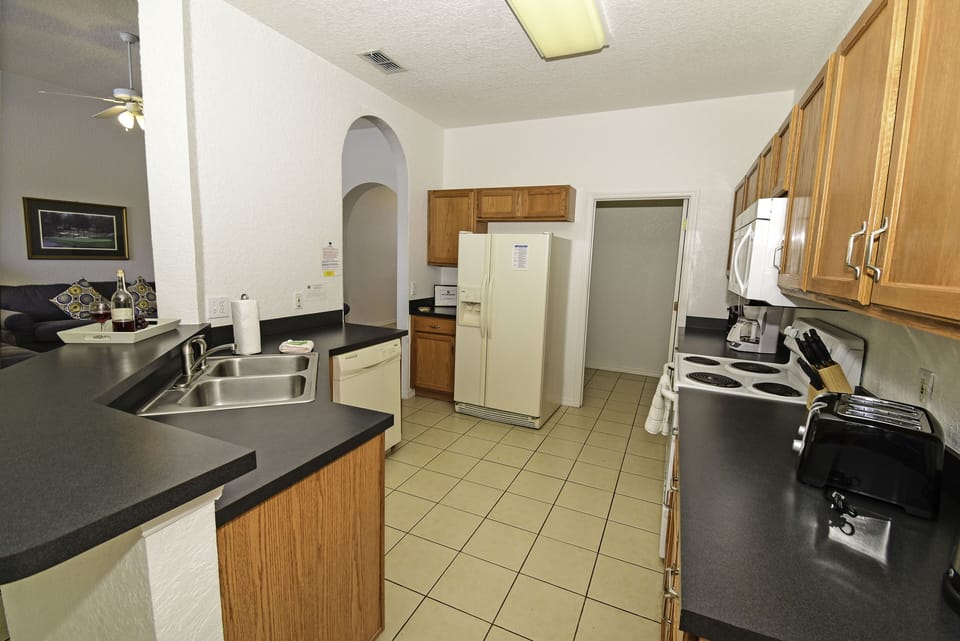 Fully equipped kitchen with tiled flooring and breakfast bar.
