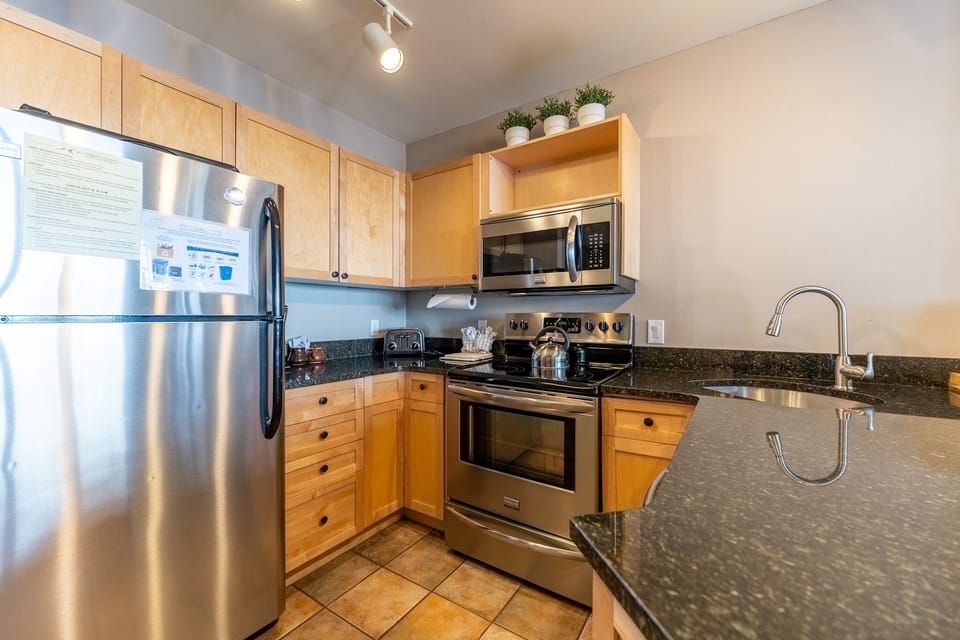 Your fully equipped kitchen awaits with stainless steel appliances, granite countertops, and warm wood cabinets perfect for preparing home-cooked meals.