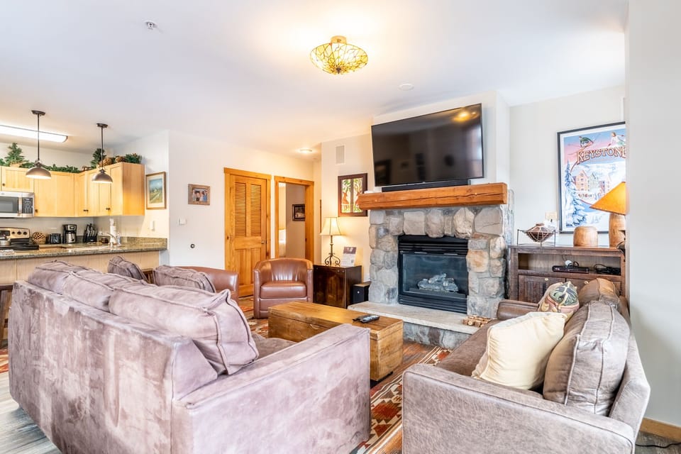 Unwind in your cozy living room with plush seating around a warm stone fireplace, perfect for mountain evenings together.
