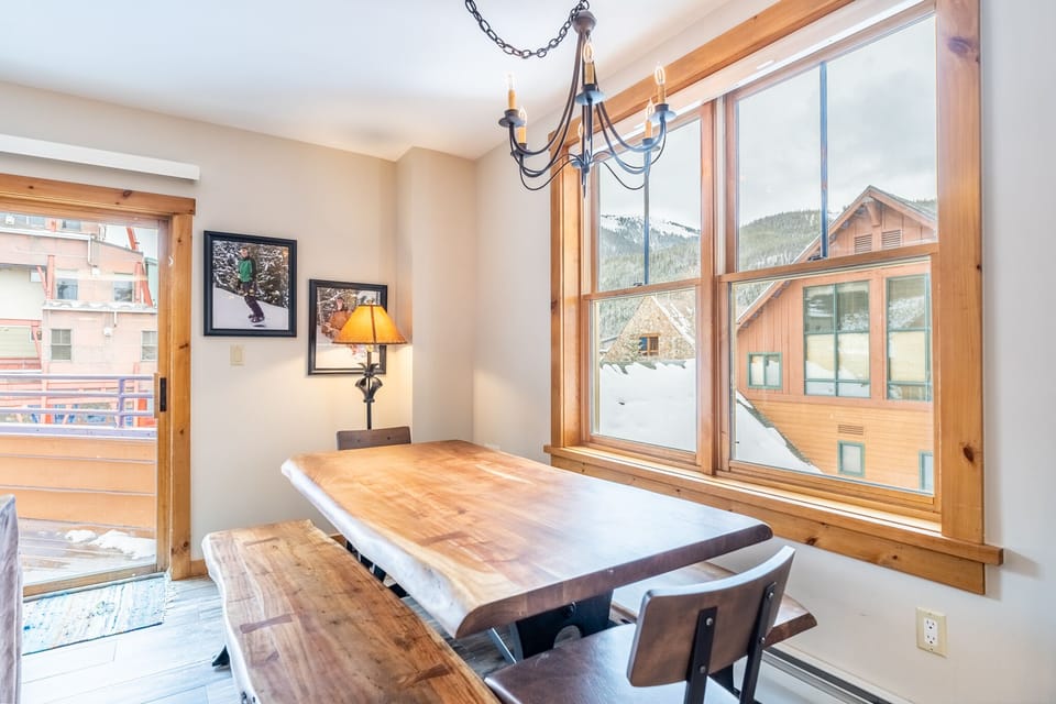 Gather around your elegant wooden dining table while soaking in breathtaking mountain views through expansive windows.