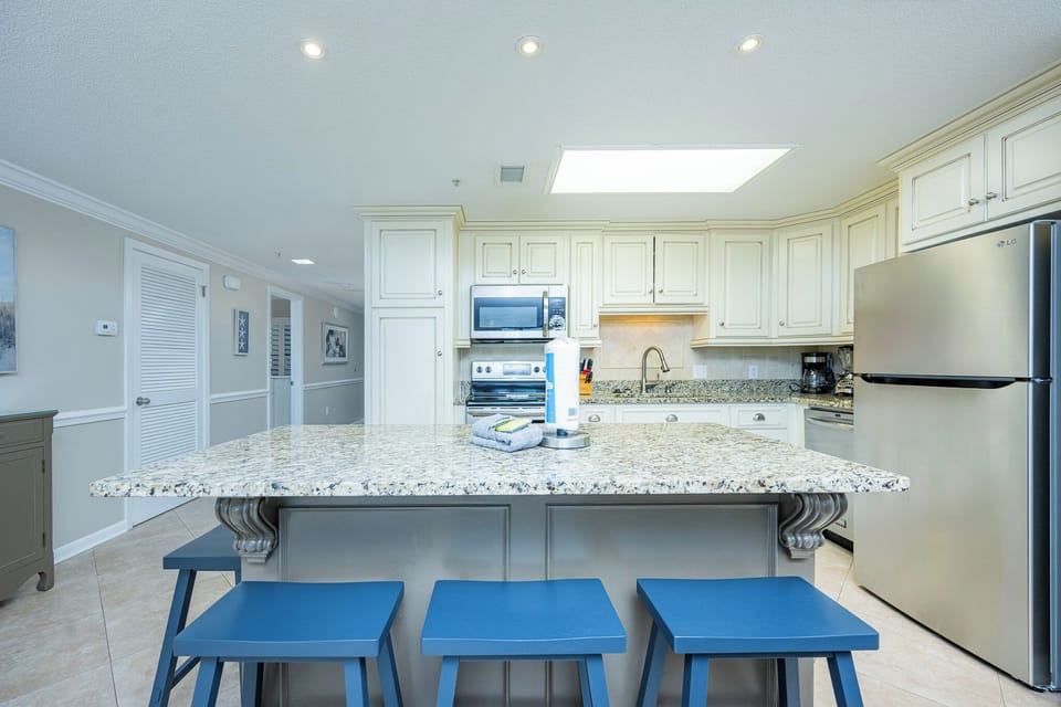 Gather around the spacious granite island with blue stools, perfect for casual meals and conversations in the kitchen