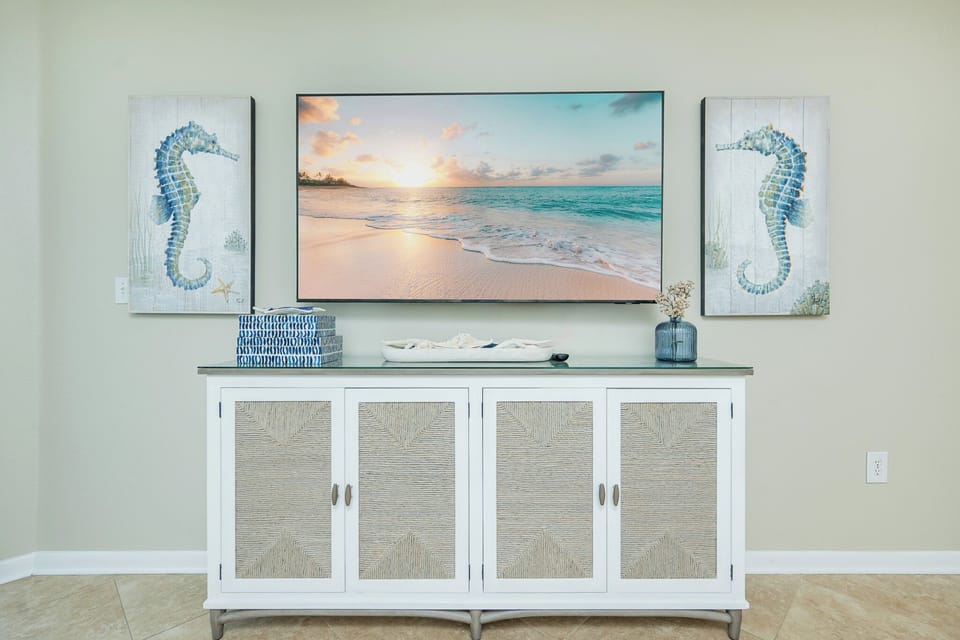 Enjoy the coastal charm of this living area, featuring seahorse artwork and a TV above a stylish console