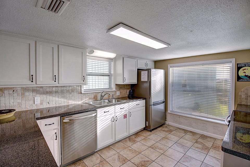 Your fully equipped kitchen features modern appliances, ample counter space, and bright natural light streaming through large windows for comfortable meal preparation.