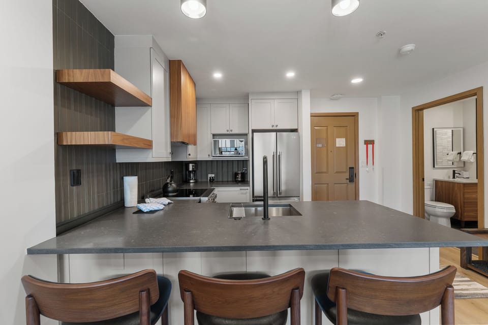 Your sleek kitchen island beckons with premium appliances and warm wood accents, perfect for cooking memorable meals together.