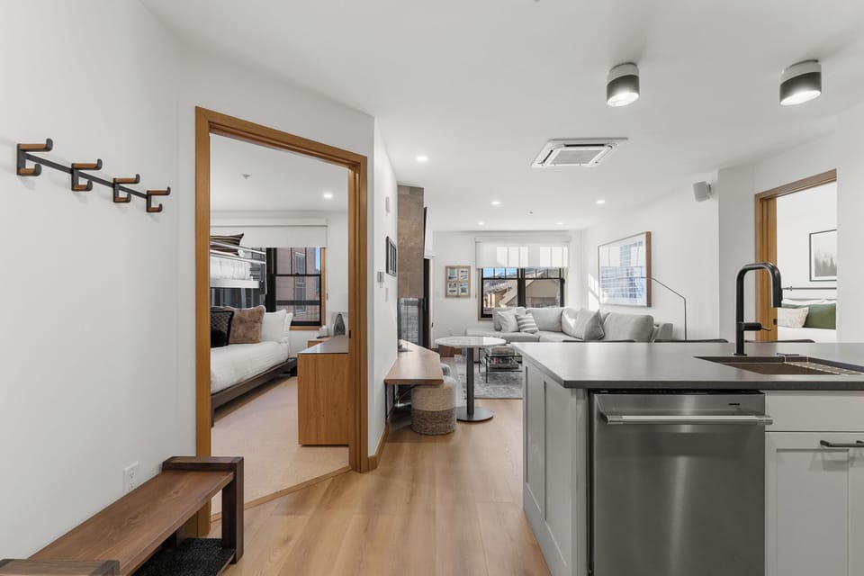 Step into your modern urban retreat where sleek kitchen flows into bright living spaces with city views through large windows.