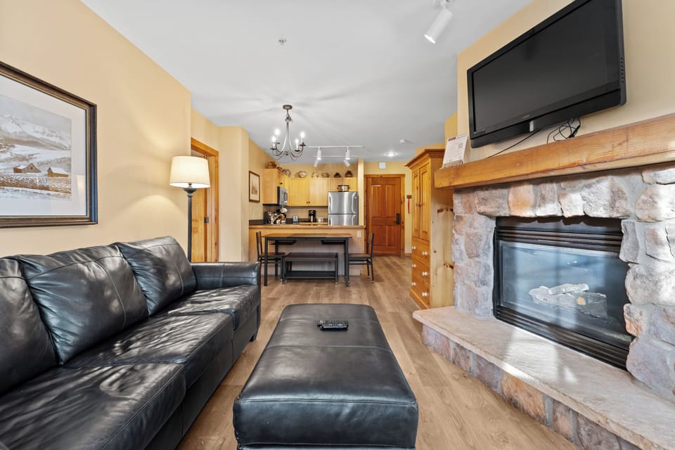 Unwind by your crackling stone fireplace while enjoying mountain views. This cozy living space flows seamlessly to your fully equipped kitchen.