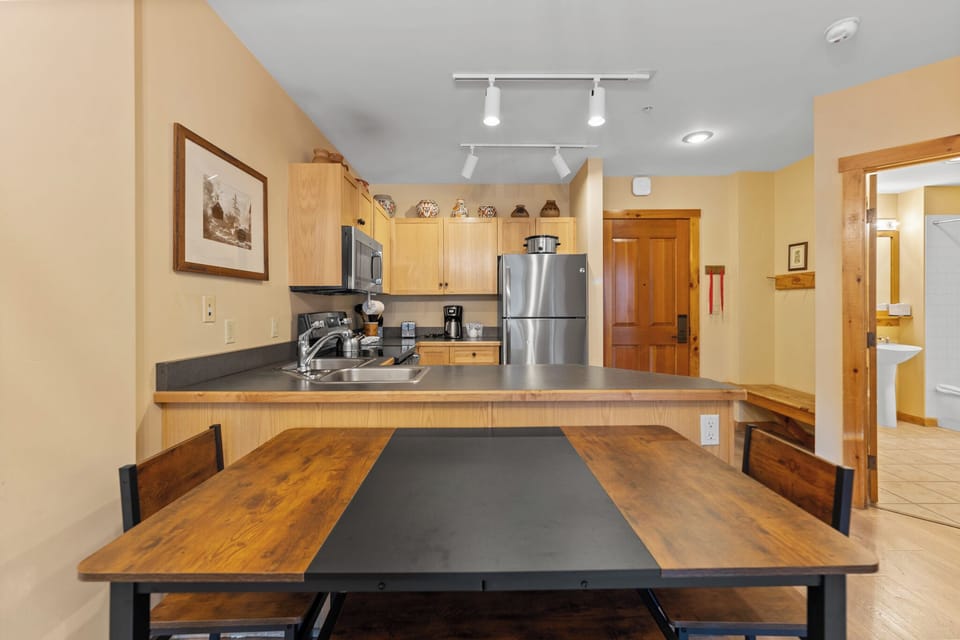 Your fully-equipped kitchen invites culinary adventures with warm wood finishes, modern appliances, and a spacious dining table perfect for memorable meals together.