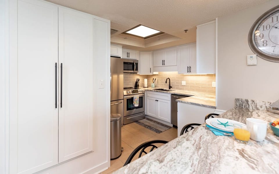 The kitchen features sleek stainless appliances, elegant white cabinetry, and a granite countertop, perfect for meal prep