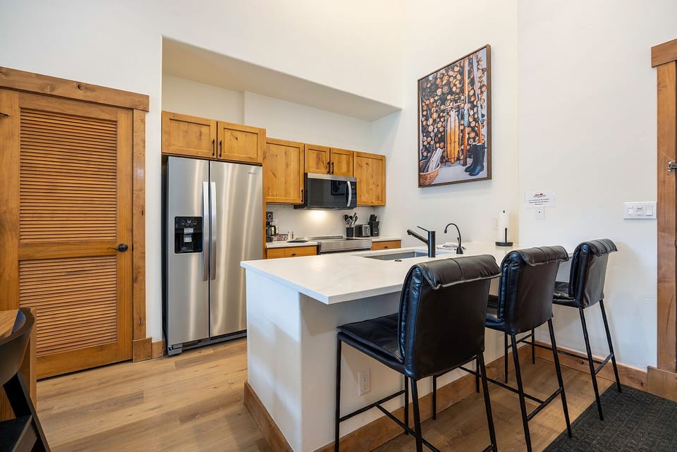 Your modern kitchen features stainless steel appliances, warm wood cabinetry, and a breakfast bar perfect for morning coffee or casual meals.