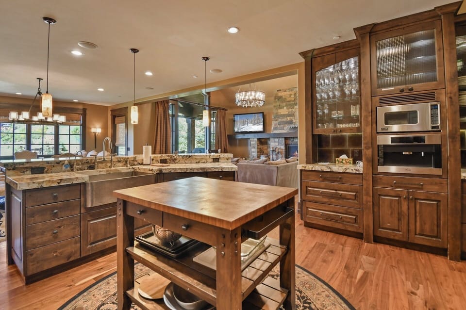 An elegant gourmet kitchen awaits with granite countertops, rich wood cabinetry, and a chef-ready island, perfect for preparing home-cooked meals while enjoying natural light streaming through large windows.