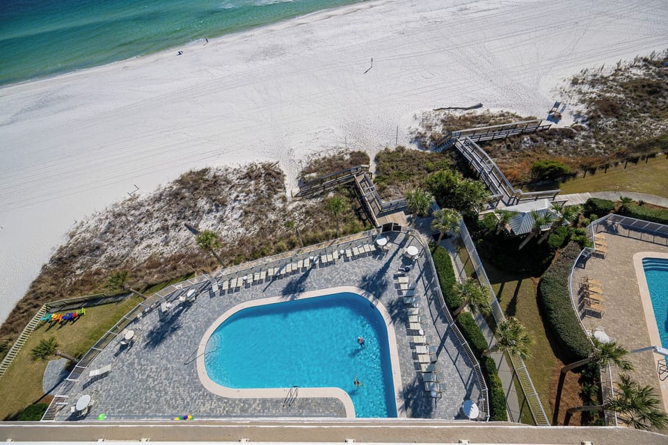 A sparkling pool invites you to cool off while the soft coast sand stretches beyond the wooden walkway