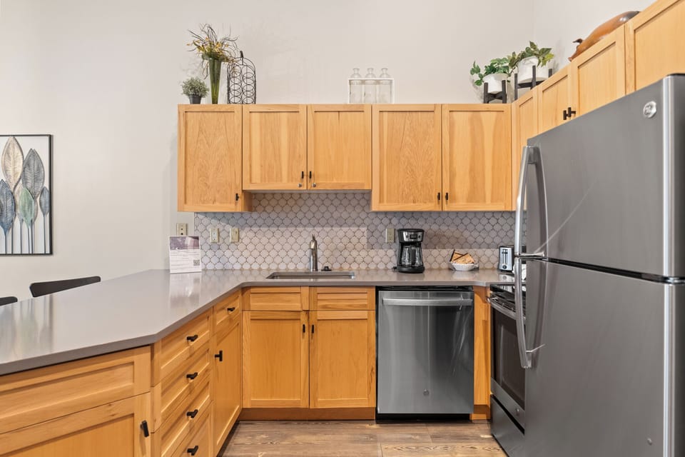 Your fully equipped kitchen features warm wood cabinetry, modern appliances, and stylish tile backsplash—perfect for preparing meals during your stay.