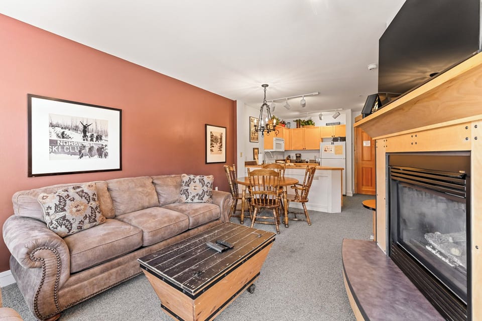 Relax in your cozy living space with warm fireplace, comfortable seating, and open kitchen for mountain getaway meals.