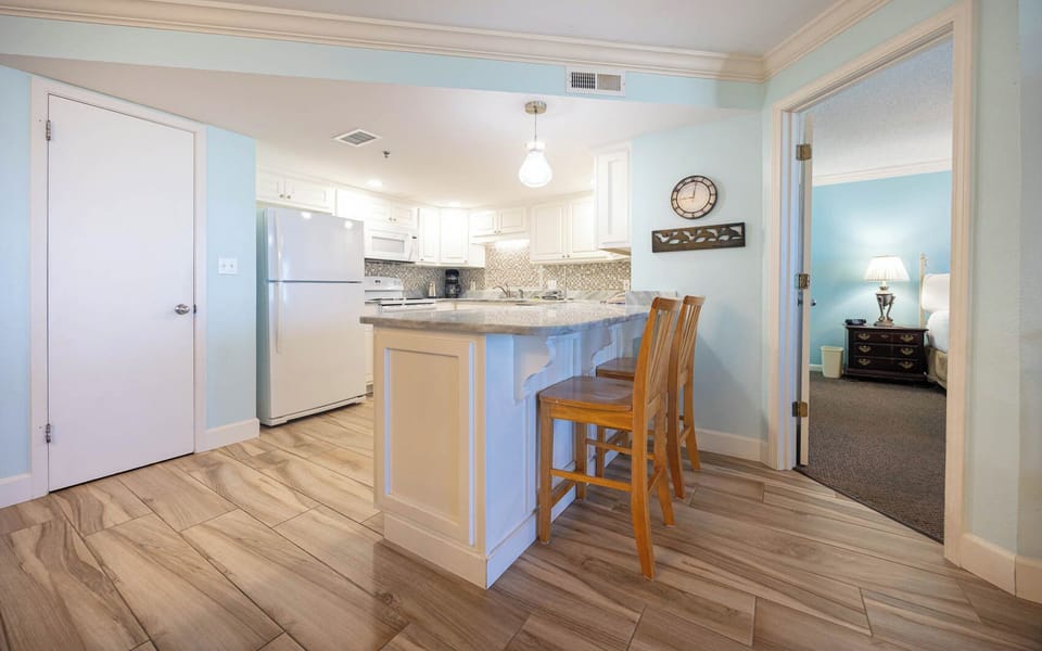 Bright kitchen area features a granite countertop breakfast bar with wooden stools