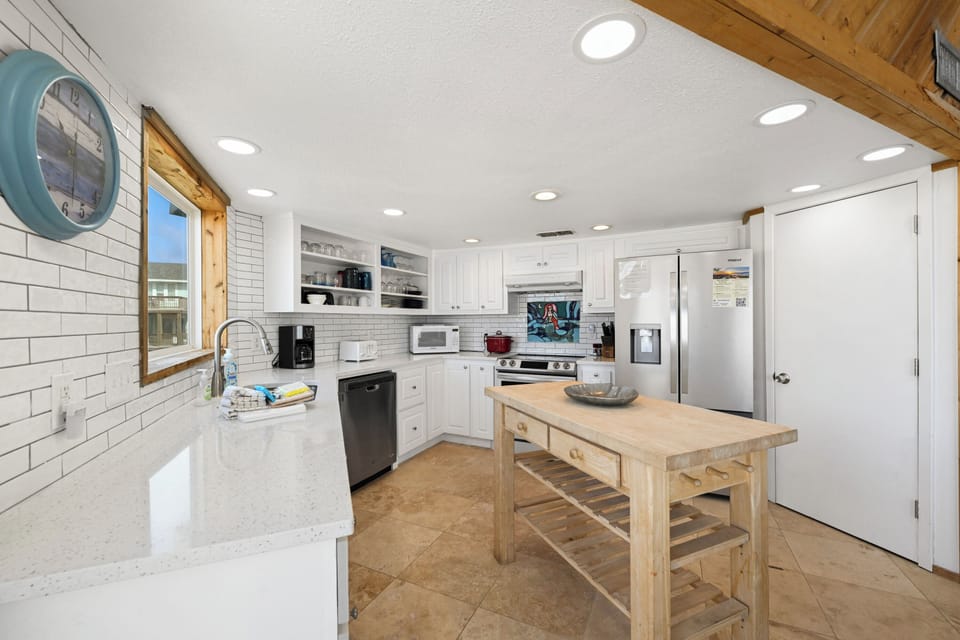 This bright, fully equipped kitchen features sparkling countertops, modern appliances, and a charming farmhouse island—perfect for preparing your favorite meals and gathering over morning coffee.