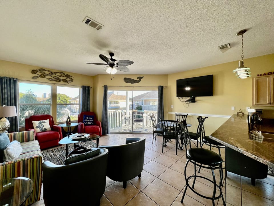 Your open living space flows seamlessly from cozy seating to dining, with balcony views and nautical touches creating a relaxing coastal atmosphere.