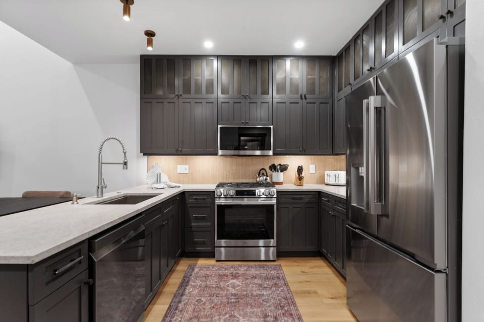 Your modern kitchen awaits with sleek dark cabinetry, stainless appliances, and warm lighting for memorable meal preparations.