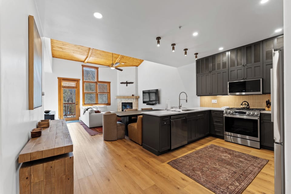 Unwind in your open-concept haven with sleek kitchen, cozy living space, and warm wood accents creating the perfect mountain retreat atmosphere.