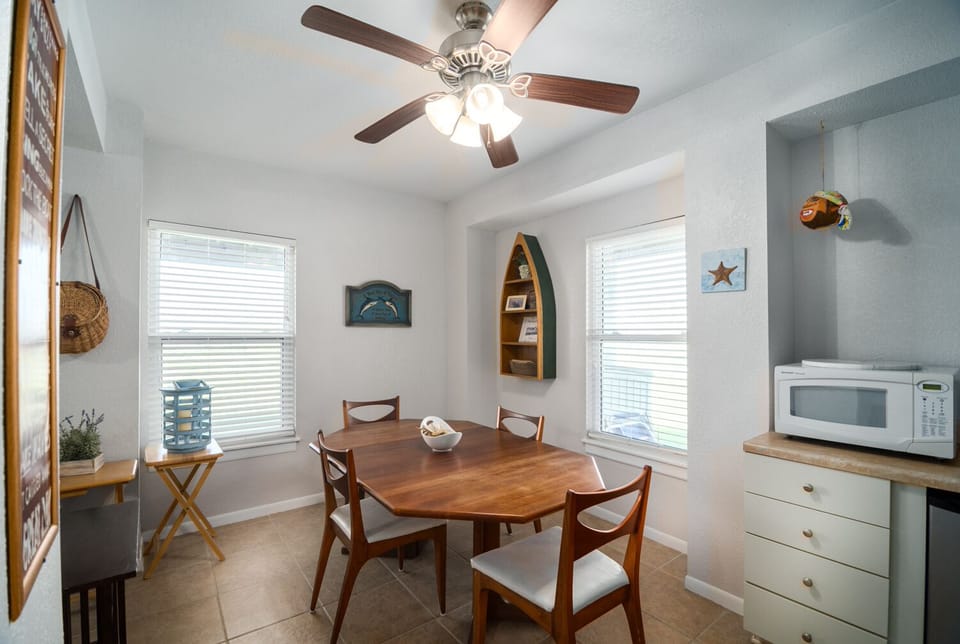 Gather around your charming dining table with coastal touches, where the ceiling fan keeps you cool during memorable meals.
